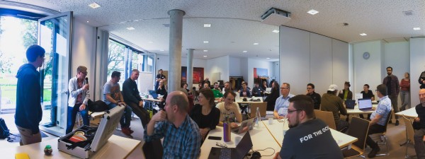 CiviCamp Hamburg 2024 Panorama von gefüllten Seminarraum, TeilnehmerInnen sitzen an Arbeitstischen mit Laptops