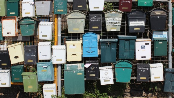 Frontalansicht vieler Briefkästen an einem Zaun